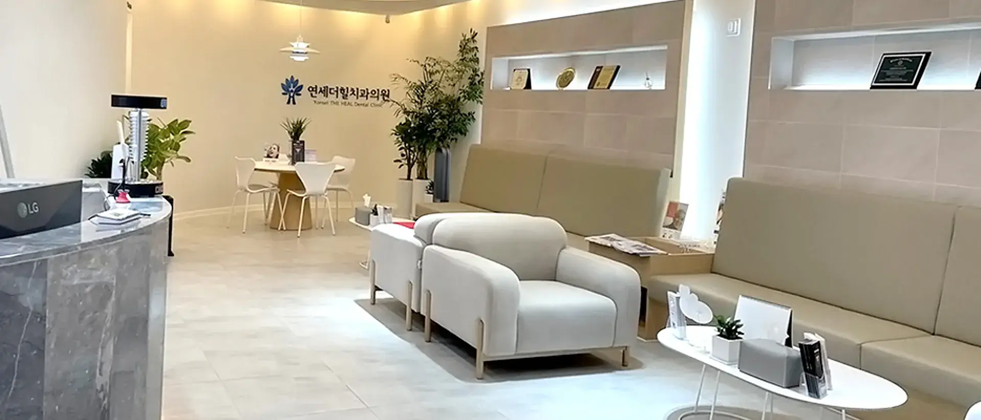 베이지 소파와 원형 테이블이 놓인 연세더힐치과 대기실